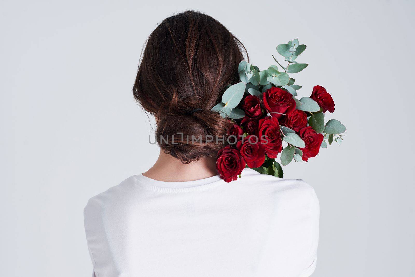 Nothing is more romantic than red roses. Studio shot of an unrecognizable woman holding flowers against a grey background. by YuriArcurs