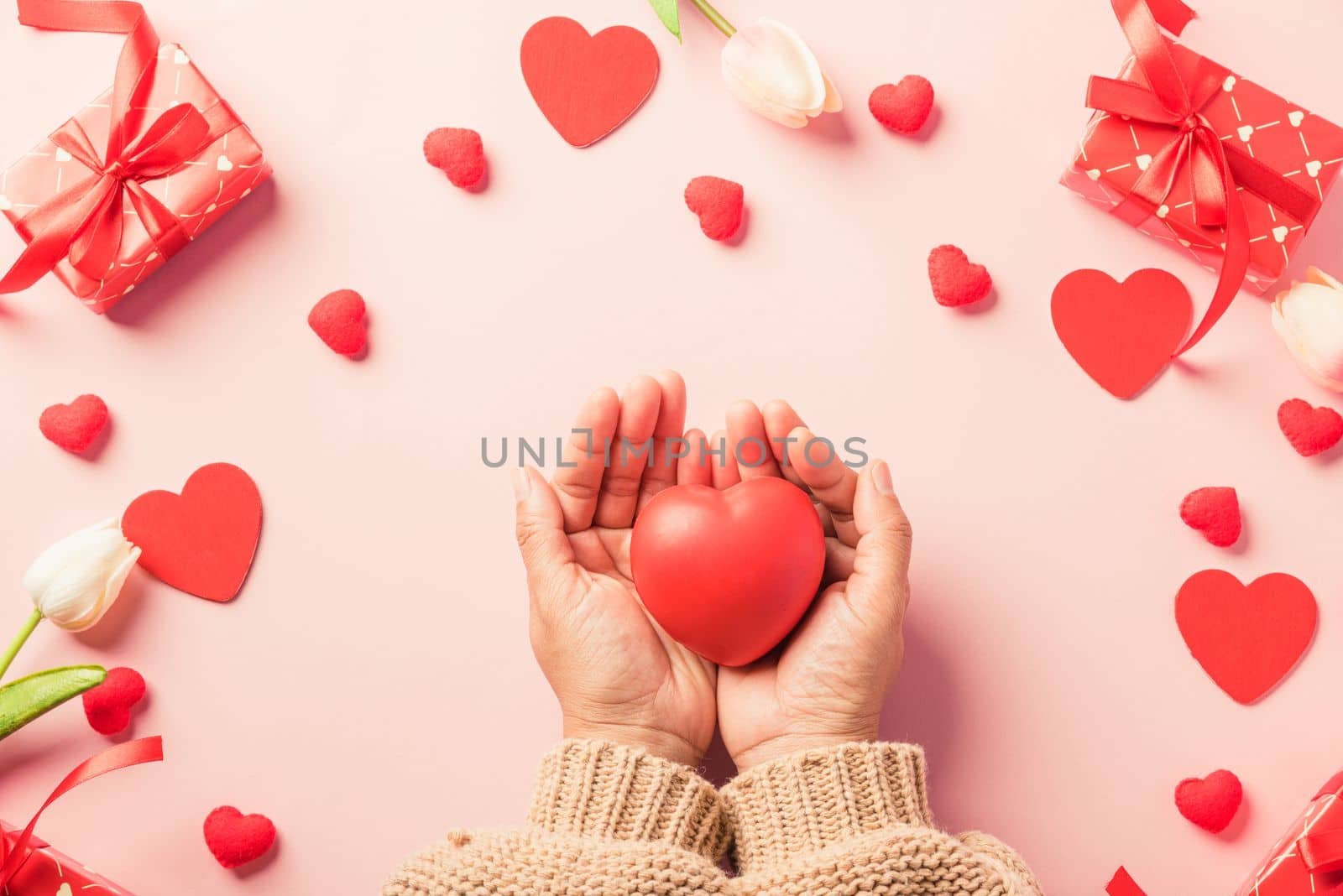 Valentine's day and birthday. Woman hands holding red heart and have gift or present box decorated surprise on pink background, Female's hand hold heart have gift box package in craft paper