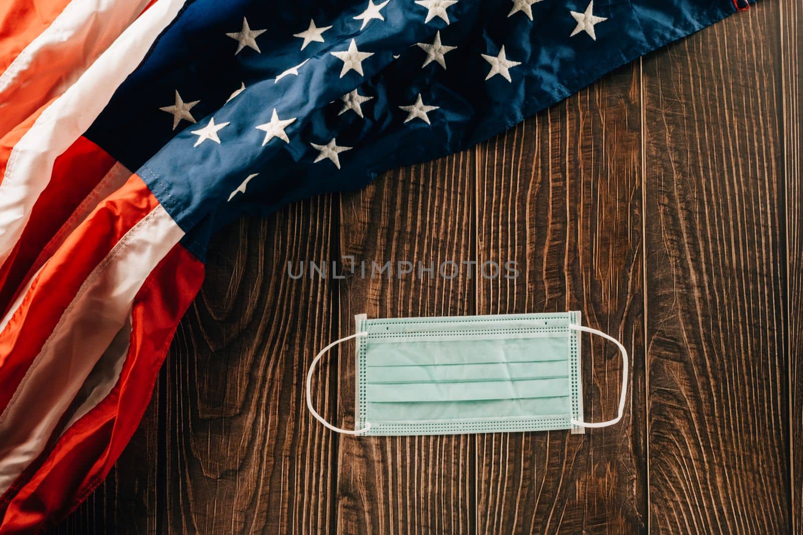 Above USA flag and face protection for coronavirus on brown old wooden background board by Sorapop