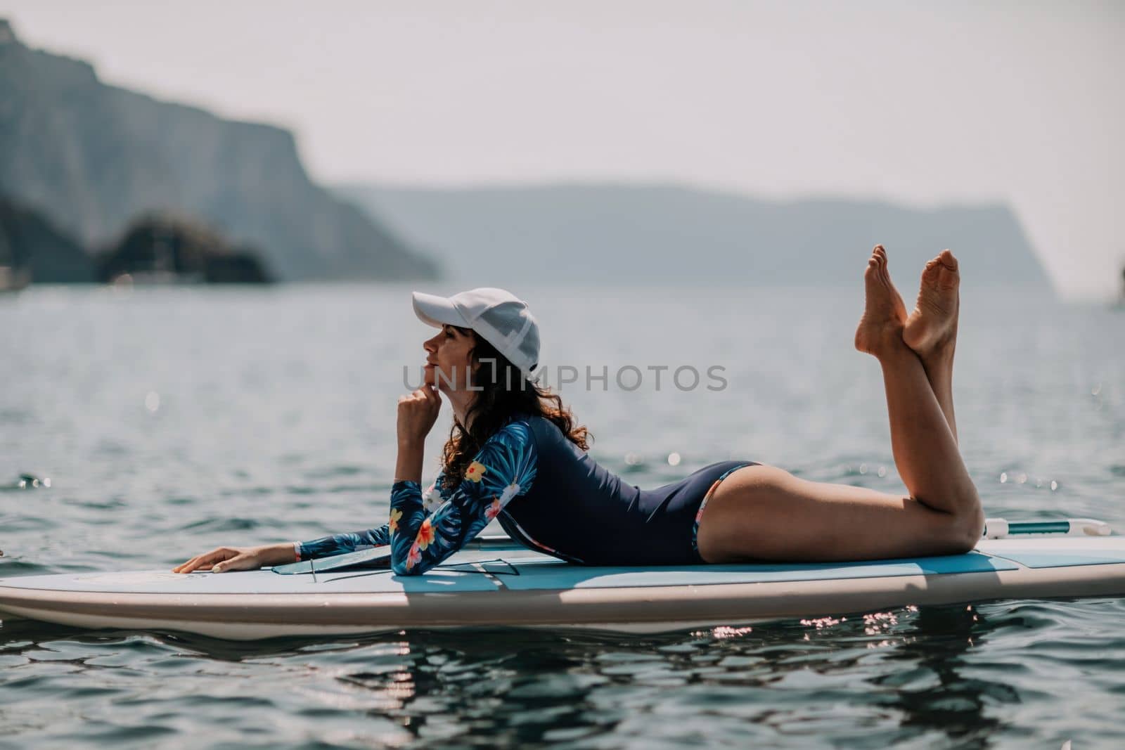 Woman sup yoga. Middle age sporty woman practising yoga pilates on paddle sup surfboard. Female stretching doing workout on sea water. Modern individual hipster outdoor summer sport activity