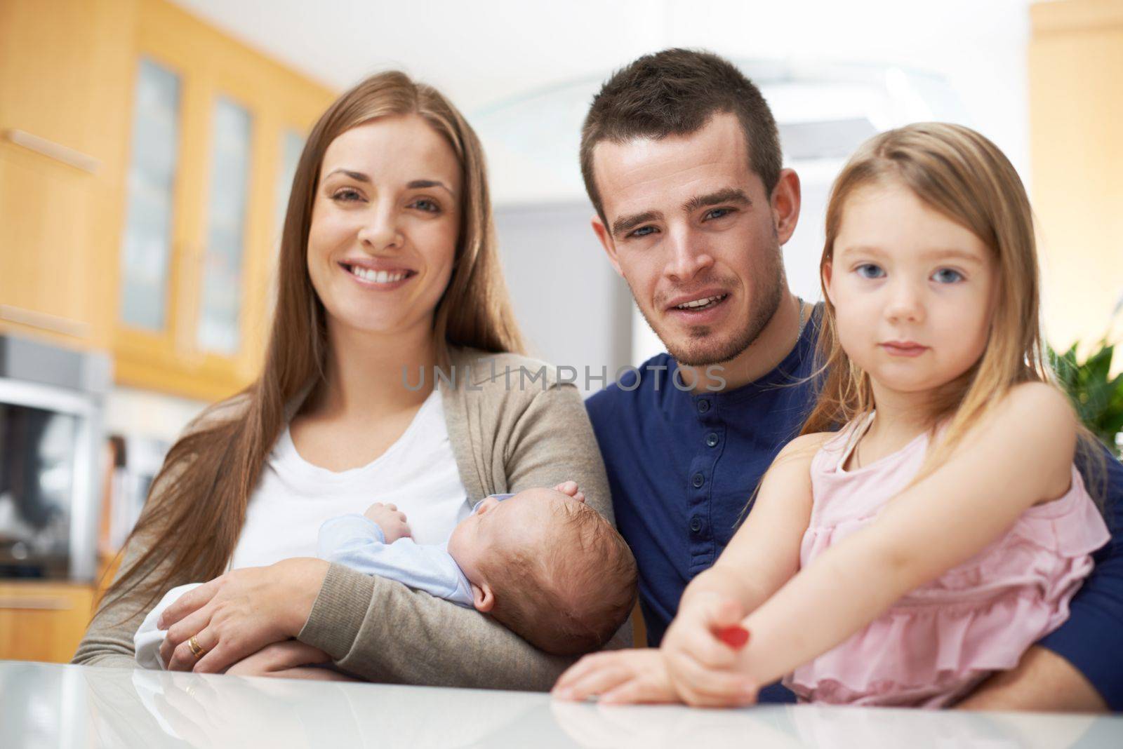 Family time is so important. A young family in their kitchen and looking at the camera. by YuriArcurs