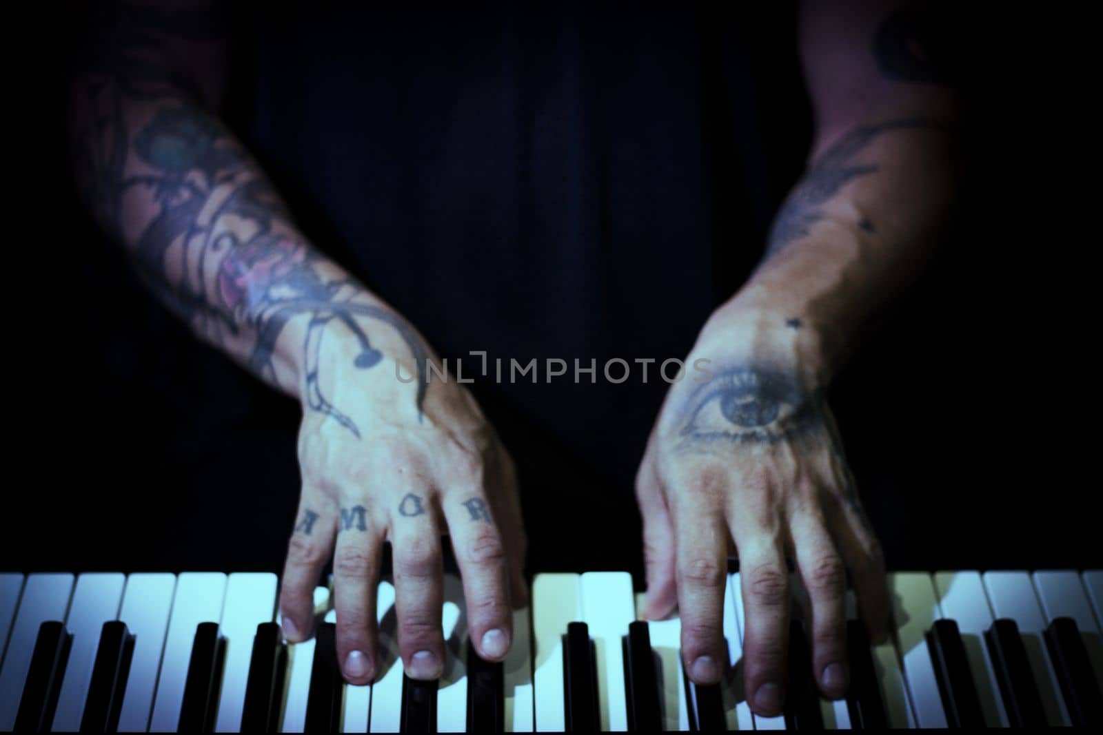 Tattooed mans hands on the keyboard of a piano by GemaIbarra
