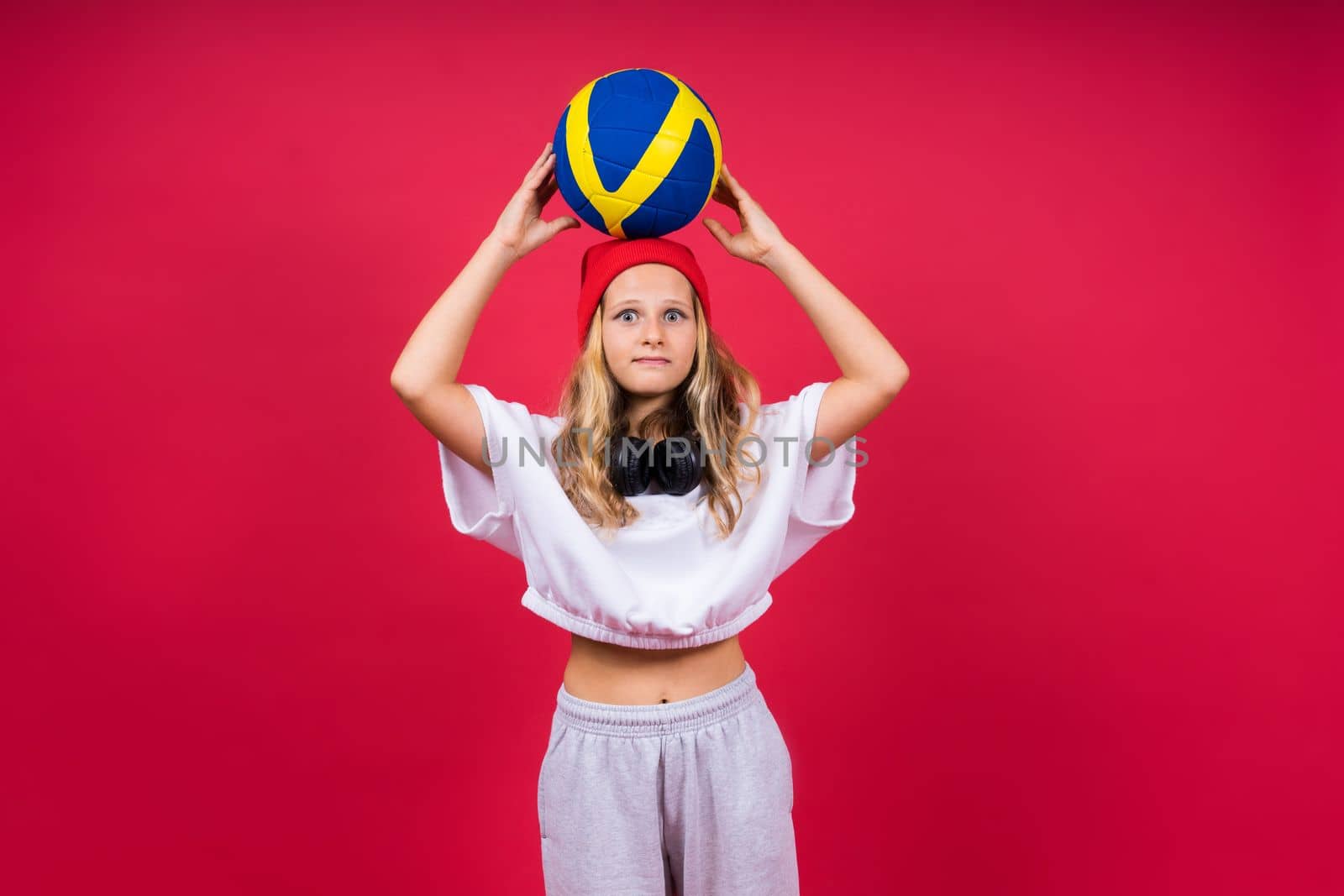 Portrait of cute eight year old girl in volleyball outfit isolated on a red background