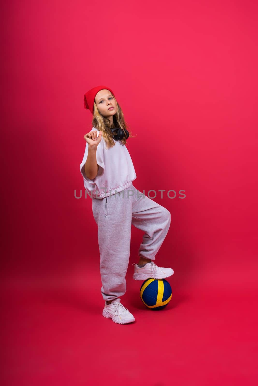Portrait of cute eight year old girl in volleyball outfit isolated on a red background