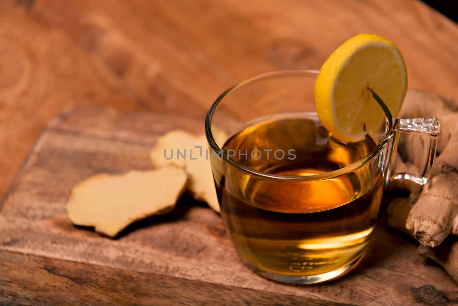 Cup of hot tea with ginger root, lemon and curcuma. Adding natural raw honey to cup of hot tea. Vitamin C drink, immune system boost