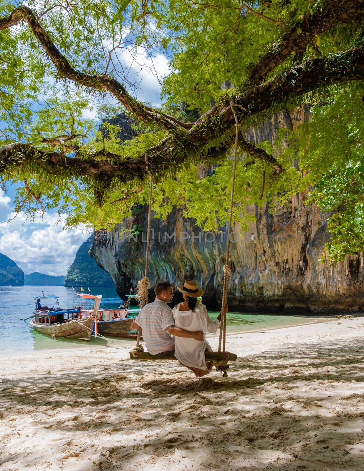Couple on a boat trip to the Tropical lagoon of Koh Loa Lading Krabi Thailand part of the Koh Hong Islands in Thailand. beautiful beach with limestone cliffs and longtail boats