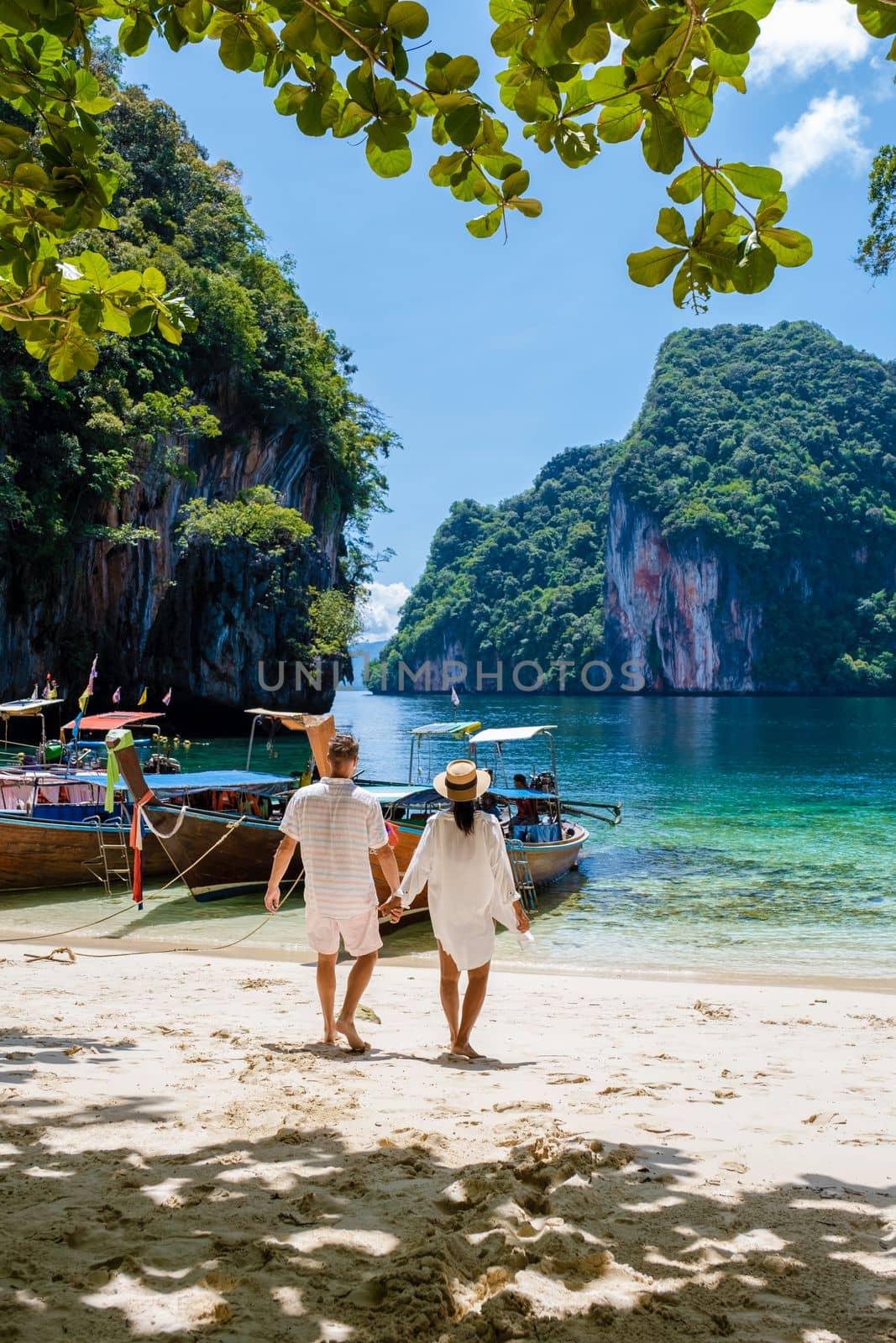 Men and women at the Tropical lagoon of Koh Loa Lading Krabi Thailand part of the Koh Hong Islands in Thailand. beautiful beach with limestone cliffs and longtail boats