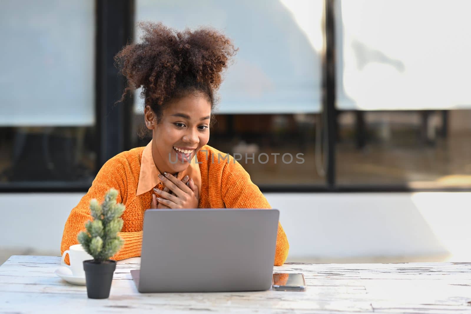 Overjoyed African American woman getting mail, read good news on laptop while sitting outdoor.