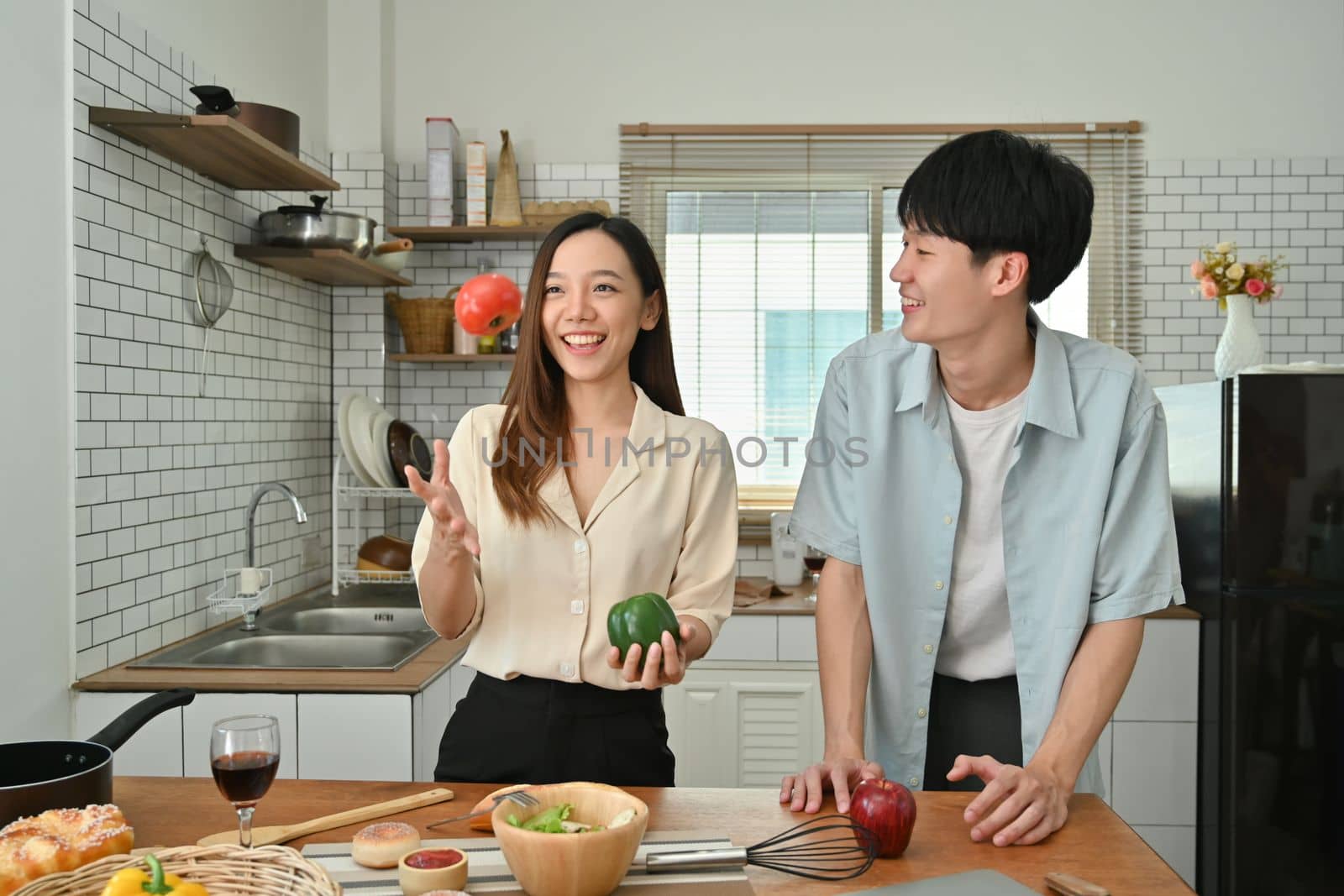Adorable young couple enjoying spending time together while cooking in modern kitchen by prathanchorruangsak