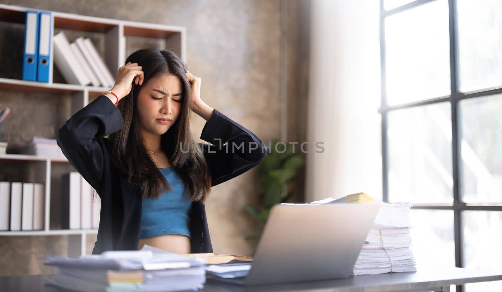 Young Asian businesswoman working on laptop computer, stressed has a headache and thinks hard from work at the office...