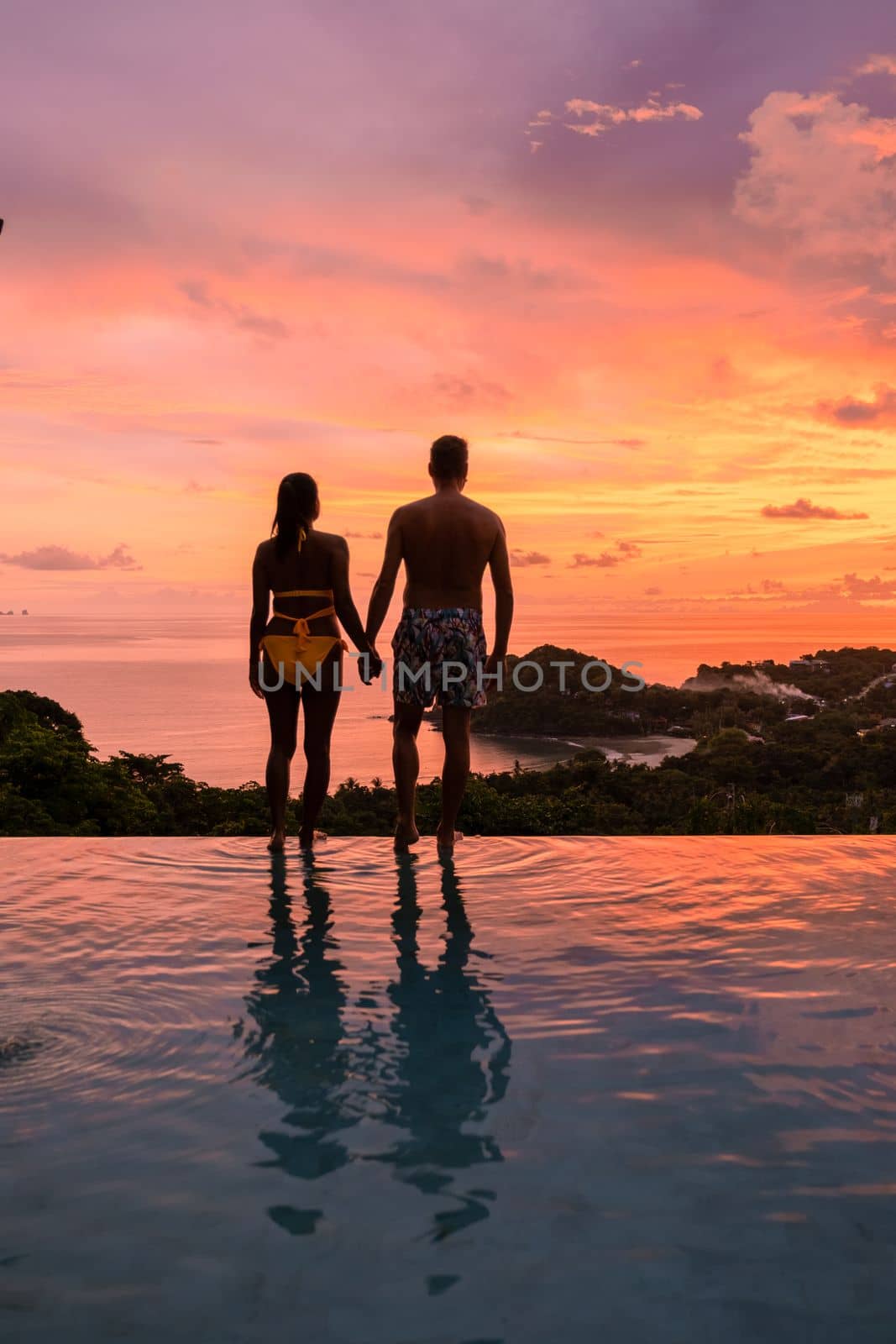 Romantic couple of men and women at a swimming pool during a vacation on a tropical island by fokkebok
