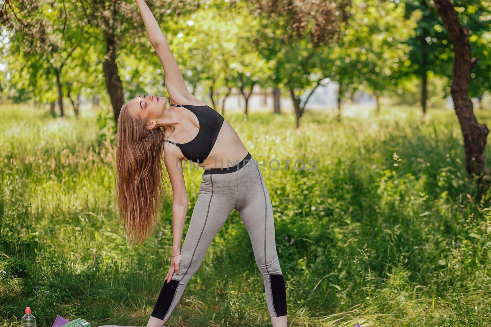 Yoga woman on green grass girl relaxes in the field. Yoga woman in green park girl doing gymnastics outdoors. Meditating woman in meditation in yoga pose practices outdoors