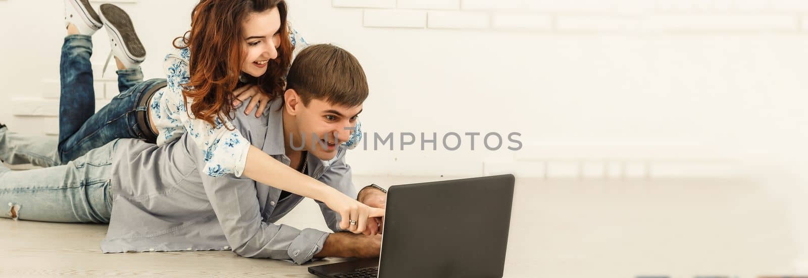 Couple shopping online at laptop computer - Two young friends watching a video on a notebook in the living room