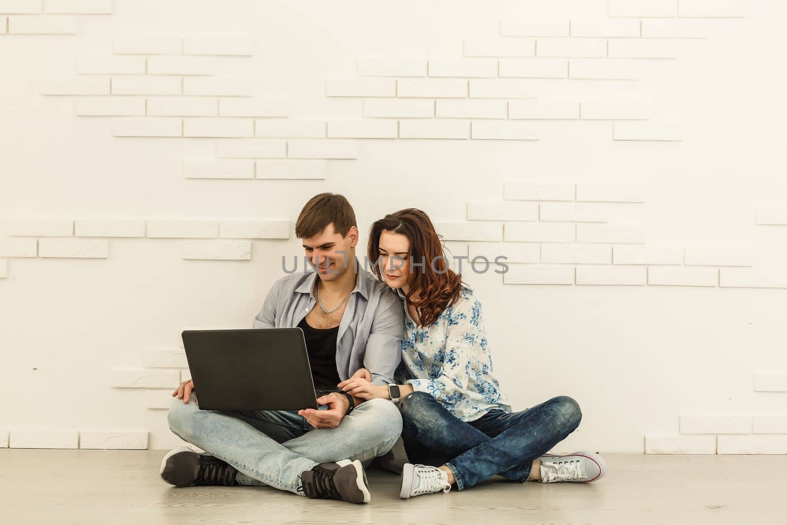 Couple shopping online at laptop computer - Two young friends watching a video on a notebook in the living room