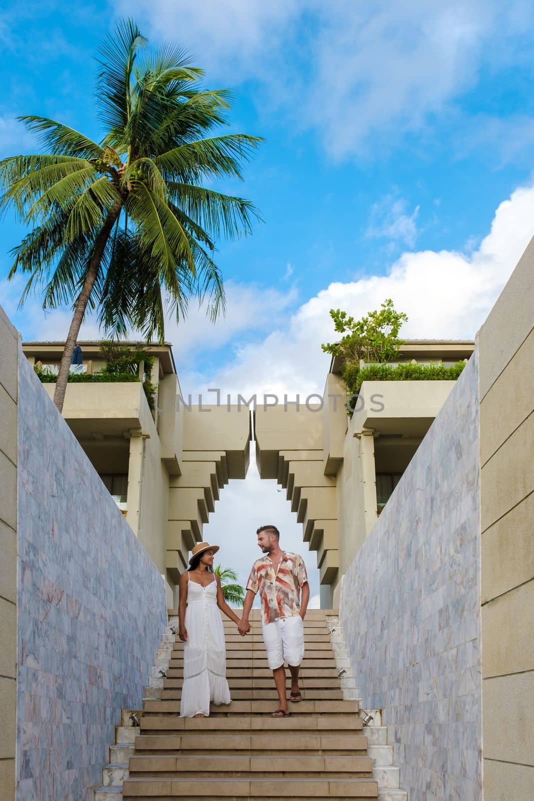couple of men and women walking at an old gate during vacation at a luxury resort in Thailand.