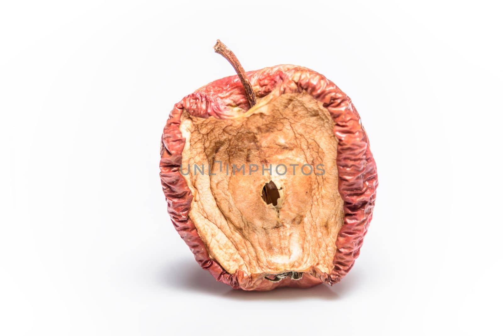 Rotting apples, decay and food waste concept with photograph of unhealthy decayed bad apple isolated on white background with clipping path cutout