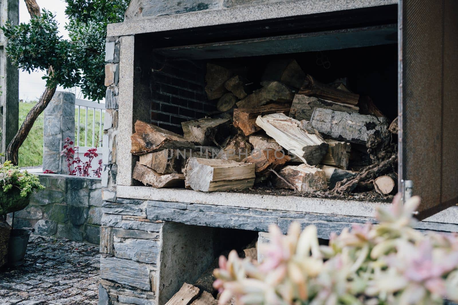 Cool Stone Barbacue with firewood inside. Chopped logs for fireplace or stove.