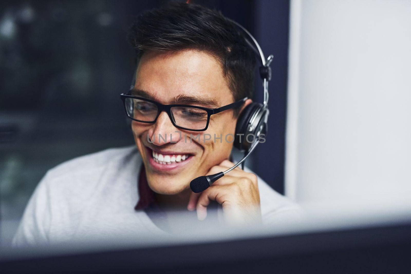 Serving clients with confidence and great communication skills. a young call centre agent working late in an office. by YuriArcurs