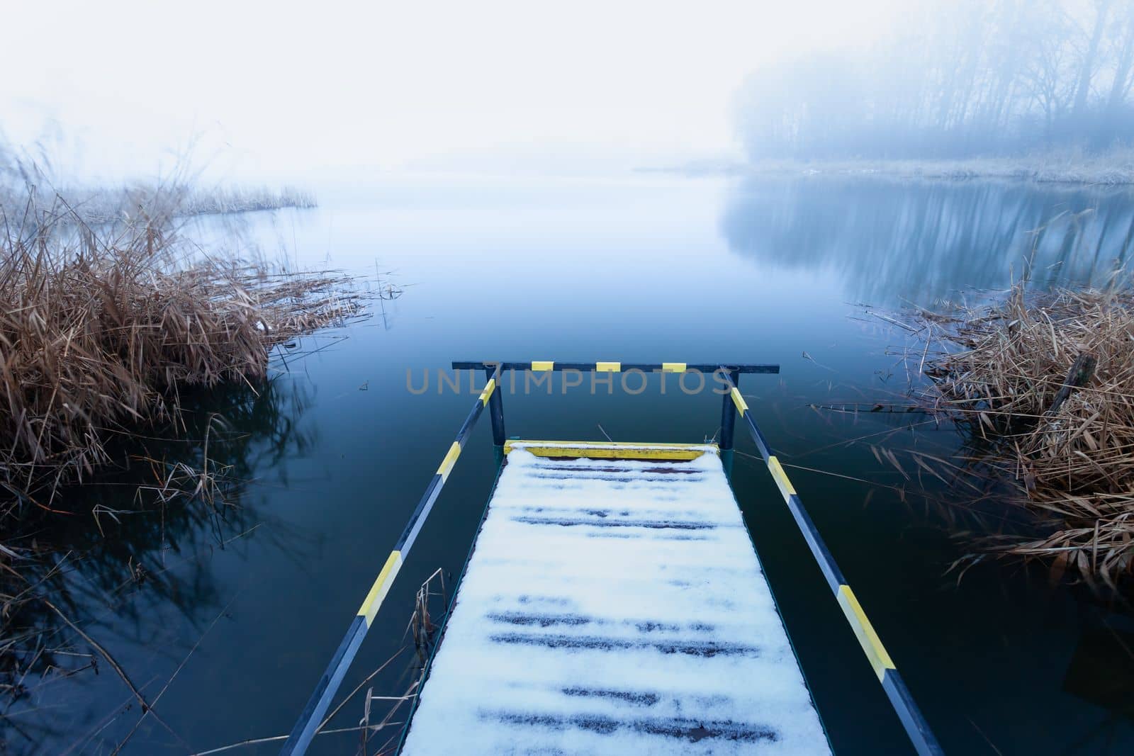 A pier with a handrail for disabled people on the shore of a lake on a foggy day, Stankow, Poland