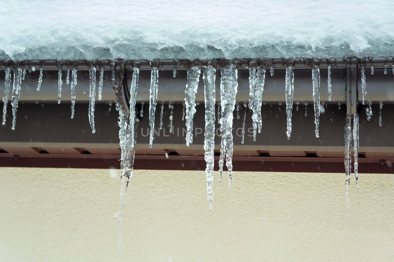 Lots of icicles hanging from the edge of the roof, winter day