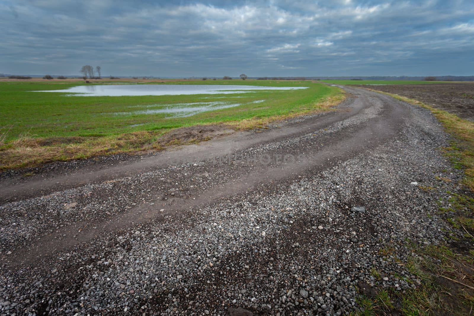 Gravel road in farmland and cloudy sky in eastern Poland by darekb22