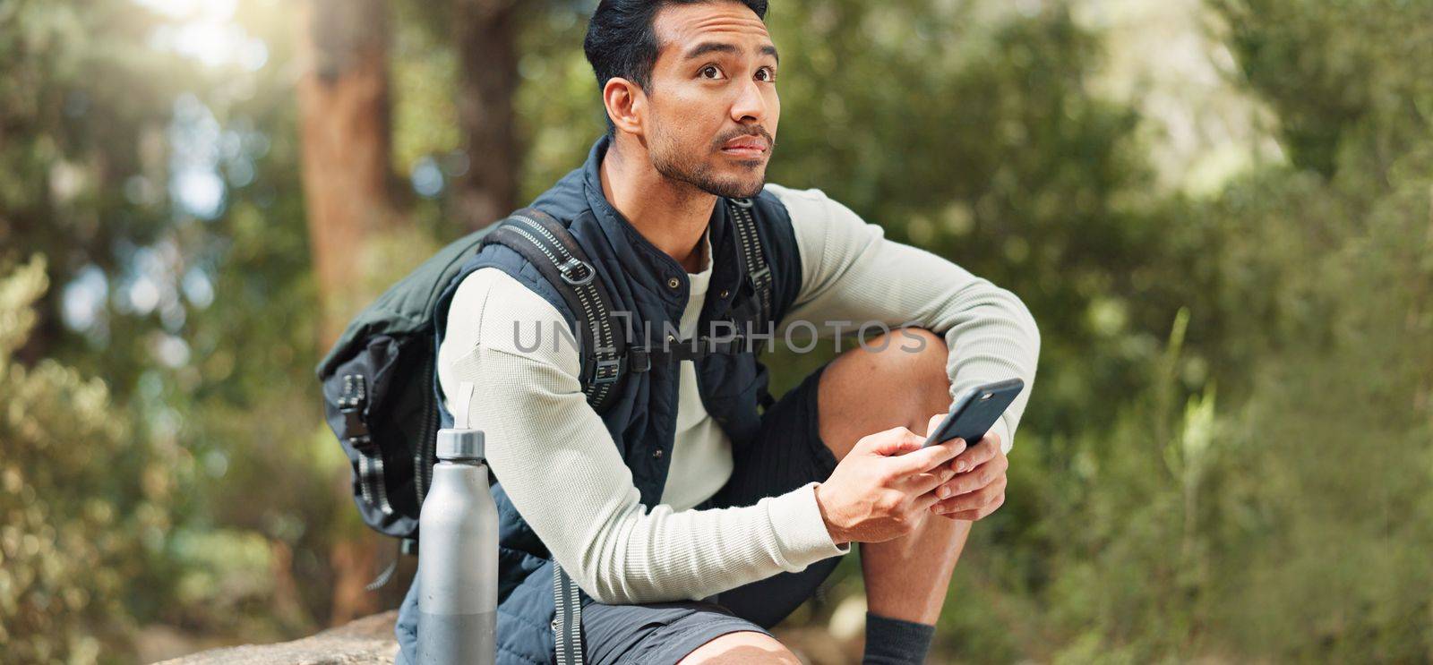 Phone, hiking and man in nature for a gps location, travel and freedom in mountains of Peru during a holiday. Young, thinking and Asian man with a mobile for communication while trekking in a forest.