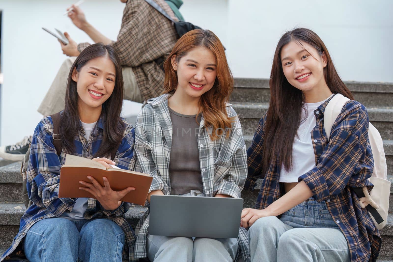 Beautiful young Asian woman college student with friends at outdoors. College student working on the college campus.