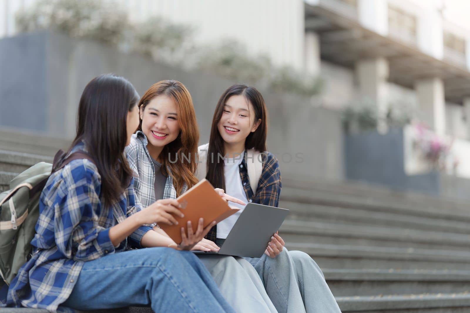 Beautiful young Asian woman college student with friends at outdoors. College student working on the college campus.