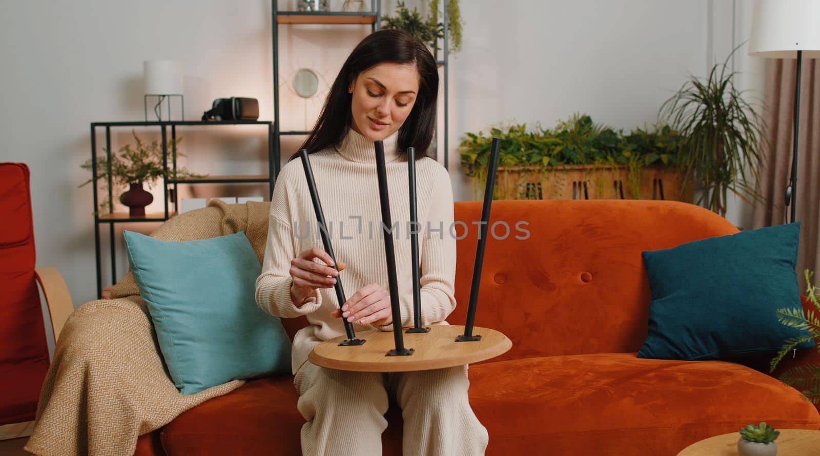 Happy brunette woman finishing assembling furniture at home. Successful table desk collect, repair fixing. Girl after moving into new apartment. Advertisement of a furniture store. Mortgage, lifestyle