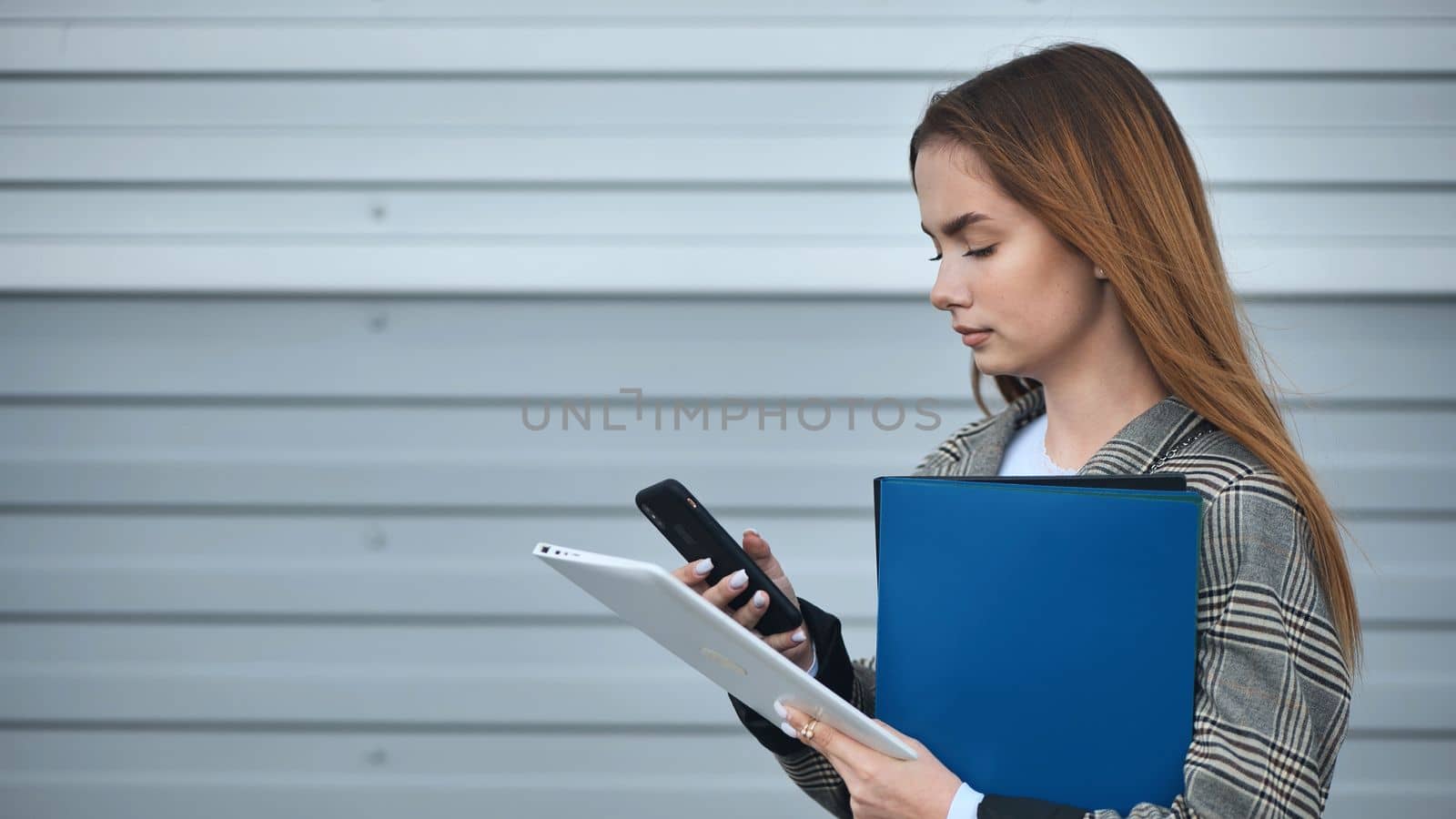 A young student works with a tablet and a phone