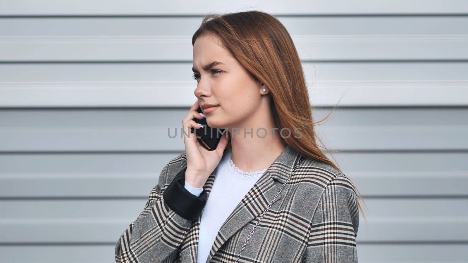A student girl in a blazer talking on the phone