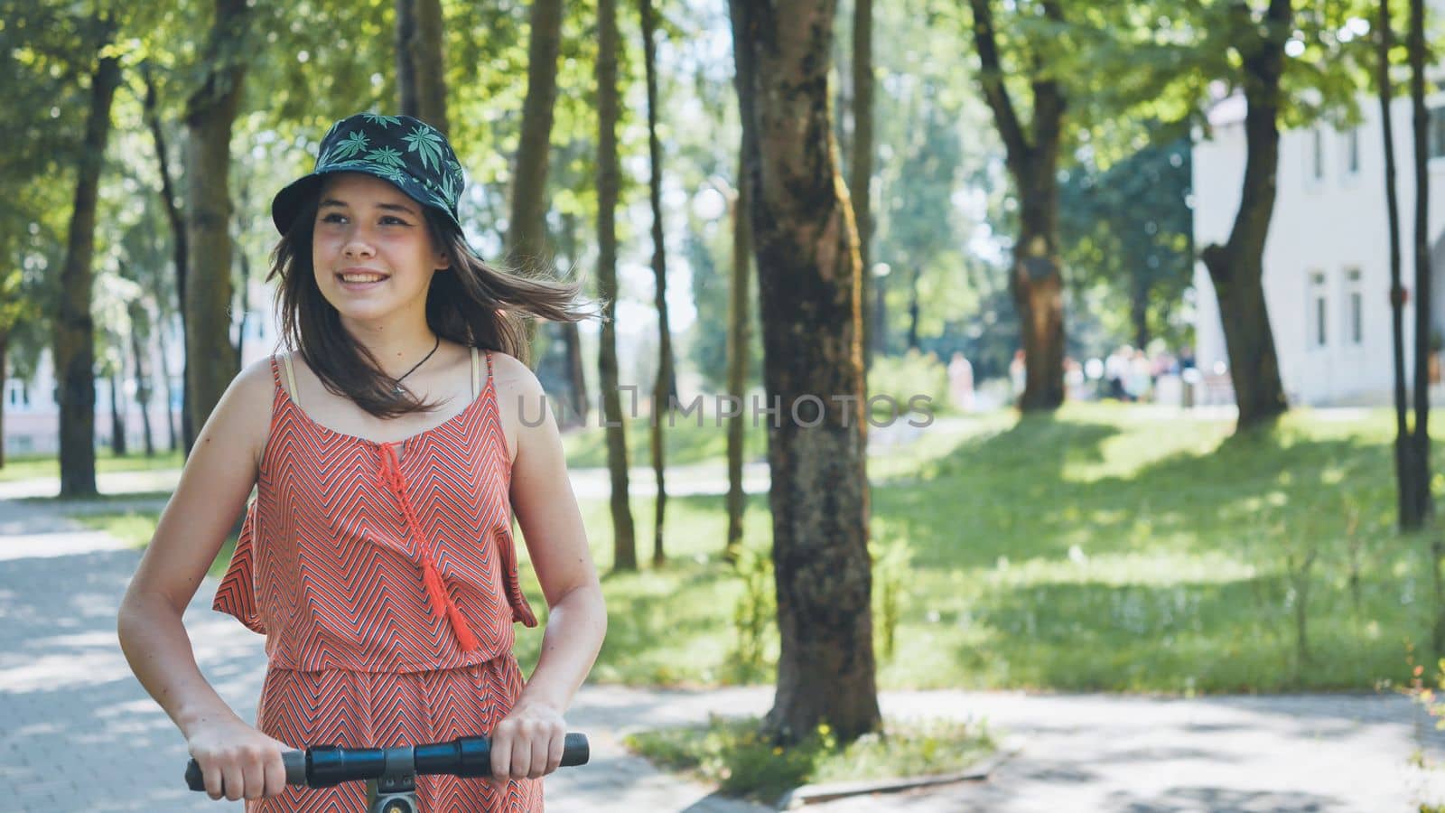 Portrait of a girl on an electric scooter riding in a park in the summer
