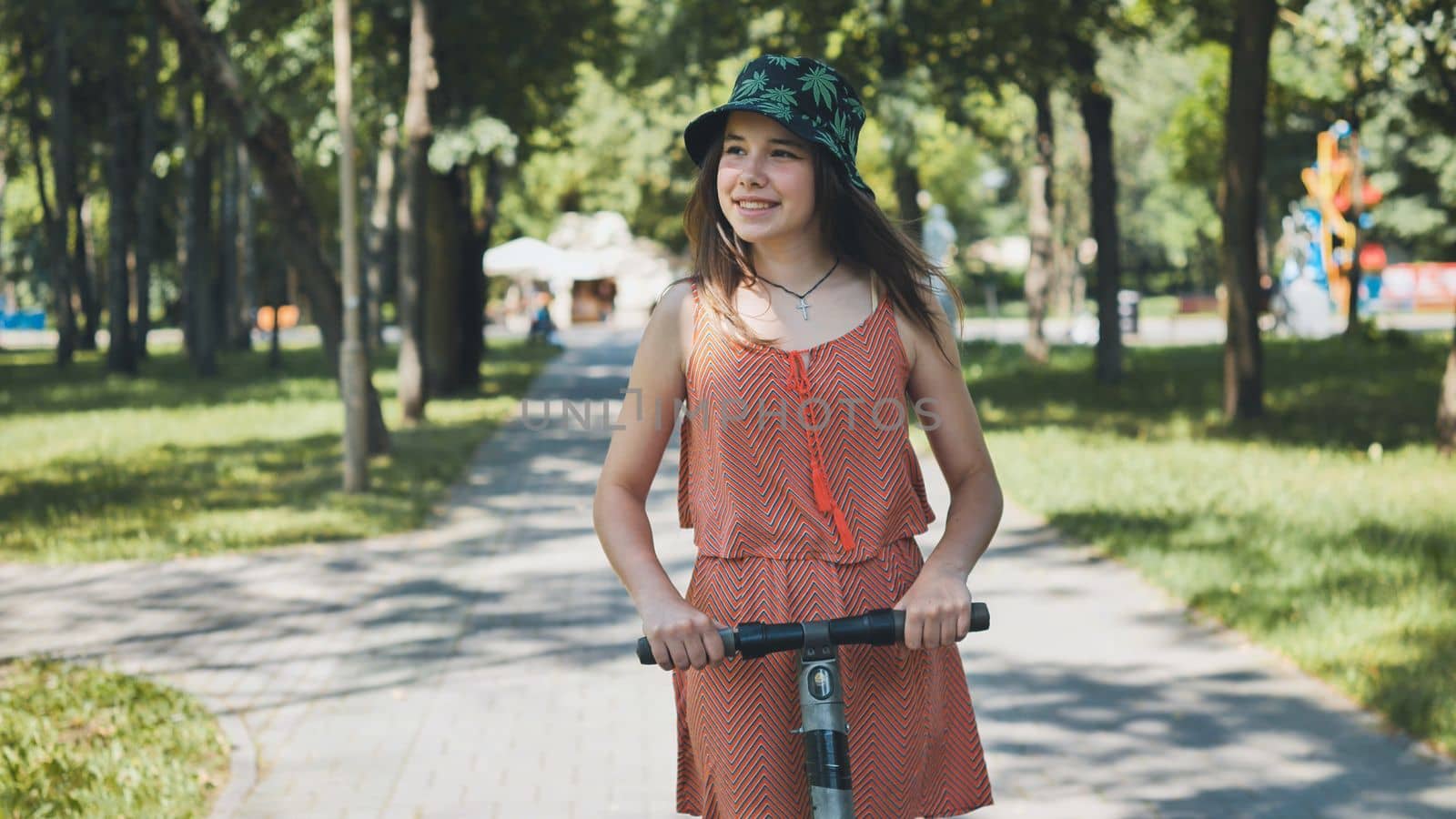 Portrait of a girl on an electric scooter riding in a park in the summer