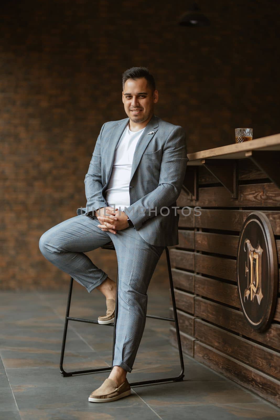 portrait of the groom in a light gray suit indoors