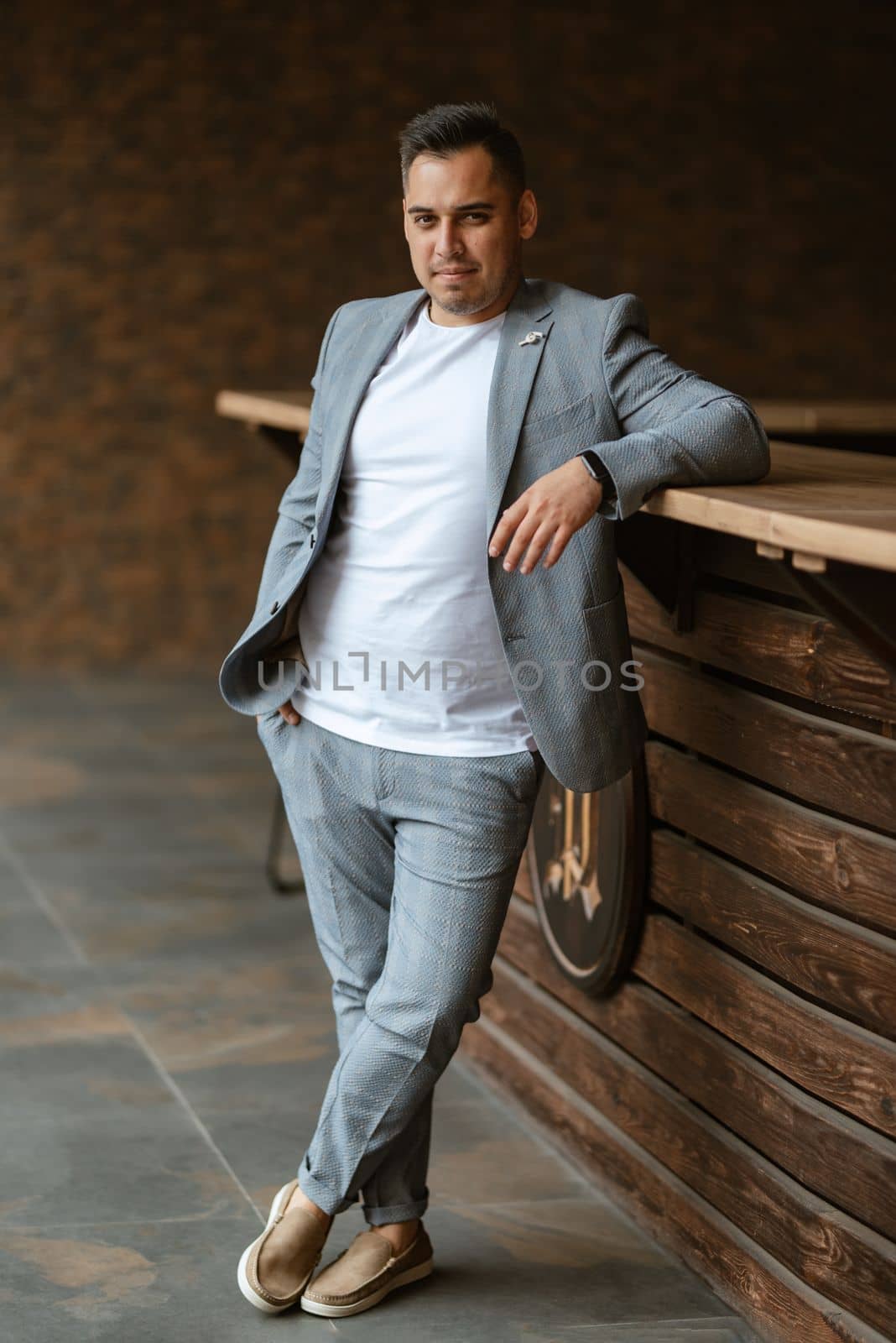 portrait of the groom in a light gray suit indoors