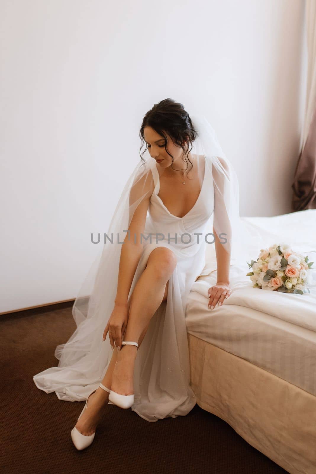 preparations for the bride with the dressing of the wedding dress in the studio