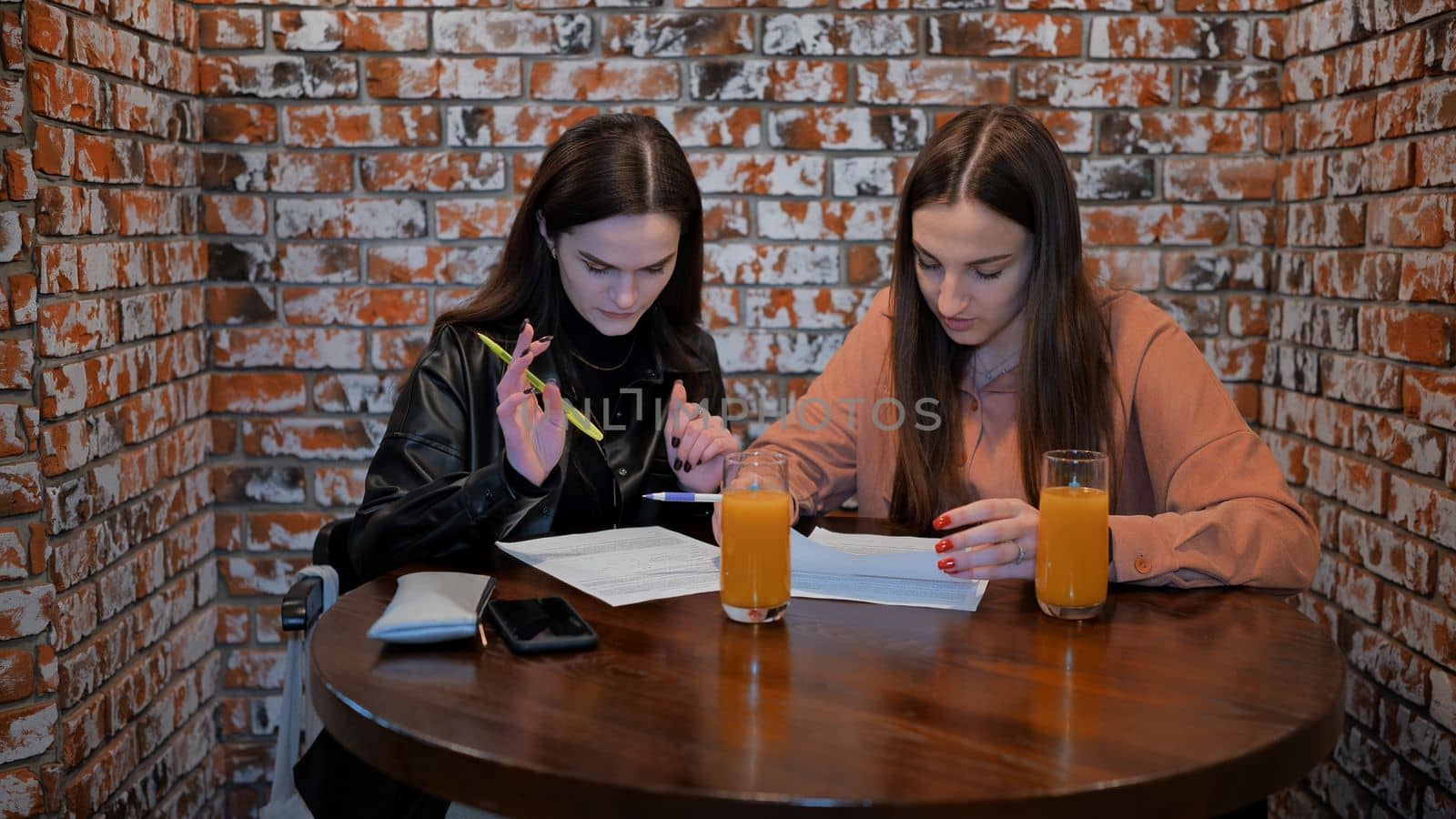 Two girls are working in a cafe with documents