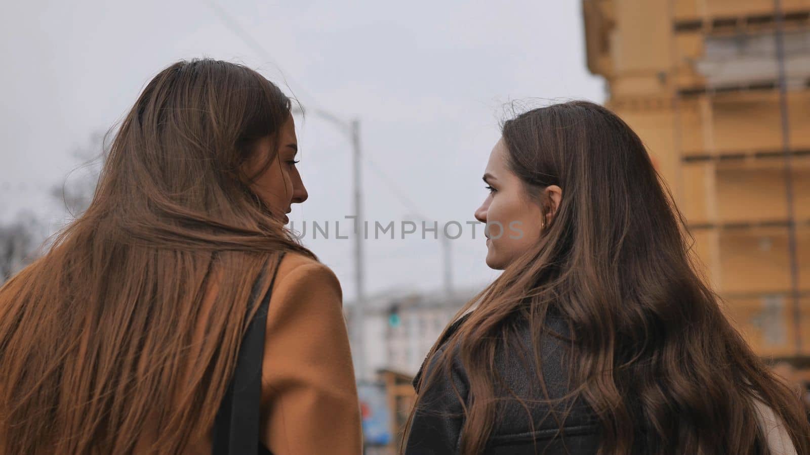 Two brown-haired girls are walking around the city