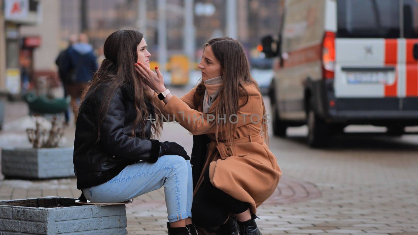 The girl is crying on the street of the city. A sympathetic passer-by calms a lonely girl. by DovidPro