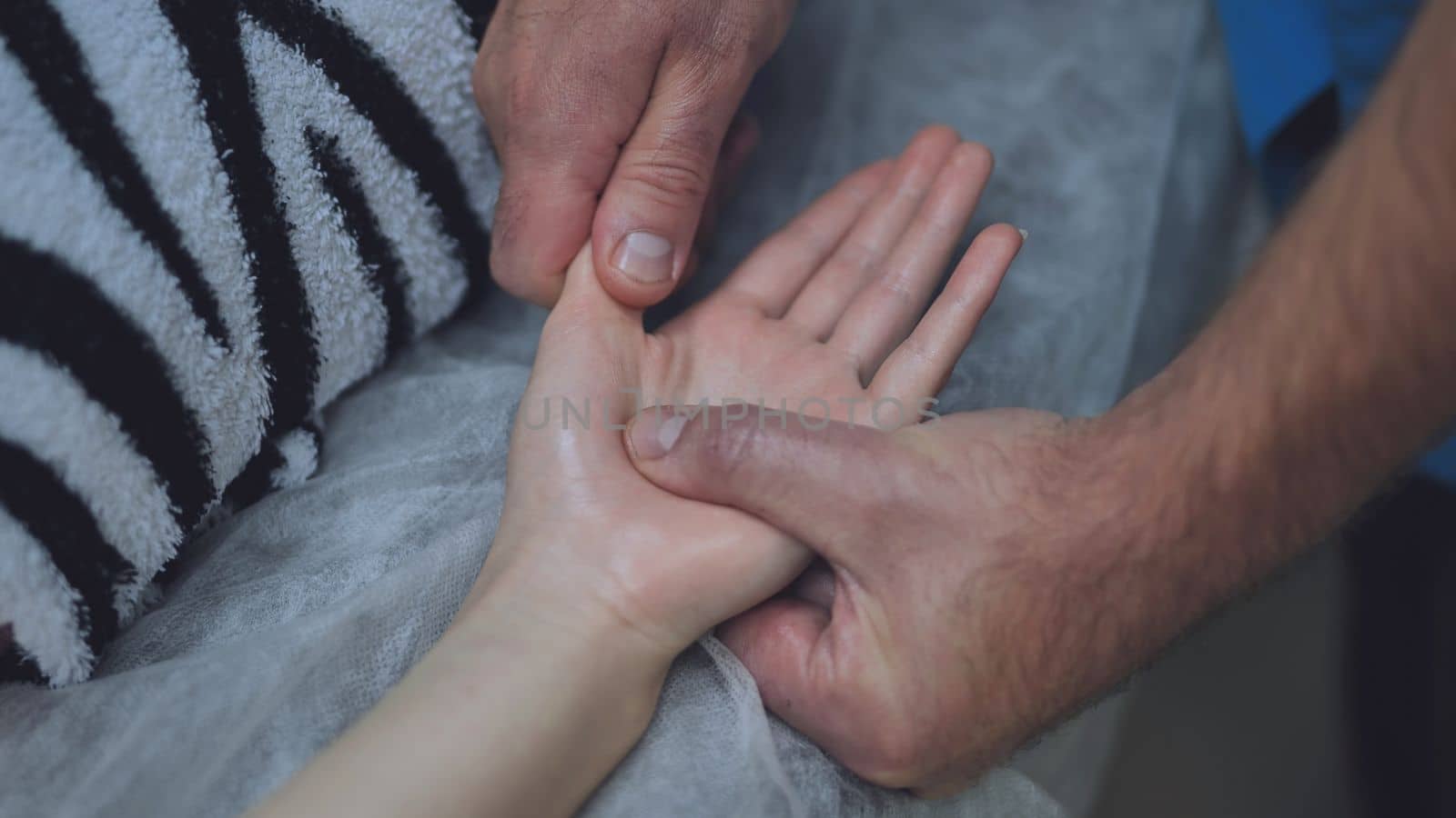 A masseur massages the wrists of a girl