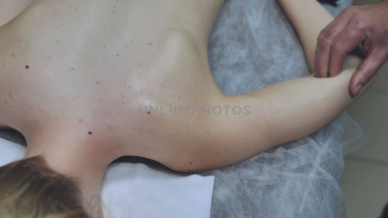 A masseur massages a girl's shoulder