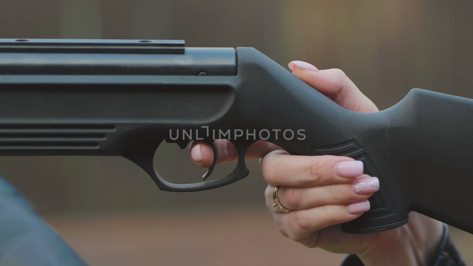 The girl is shooting from an air gun. Close-up of her hands