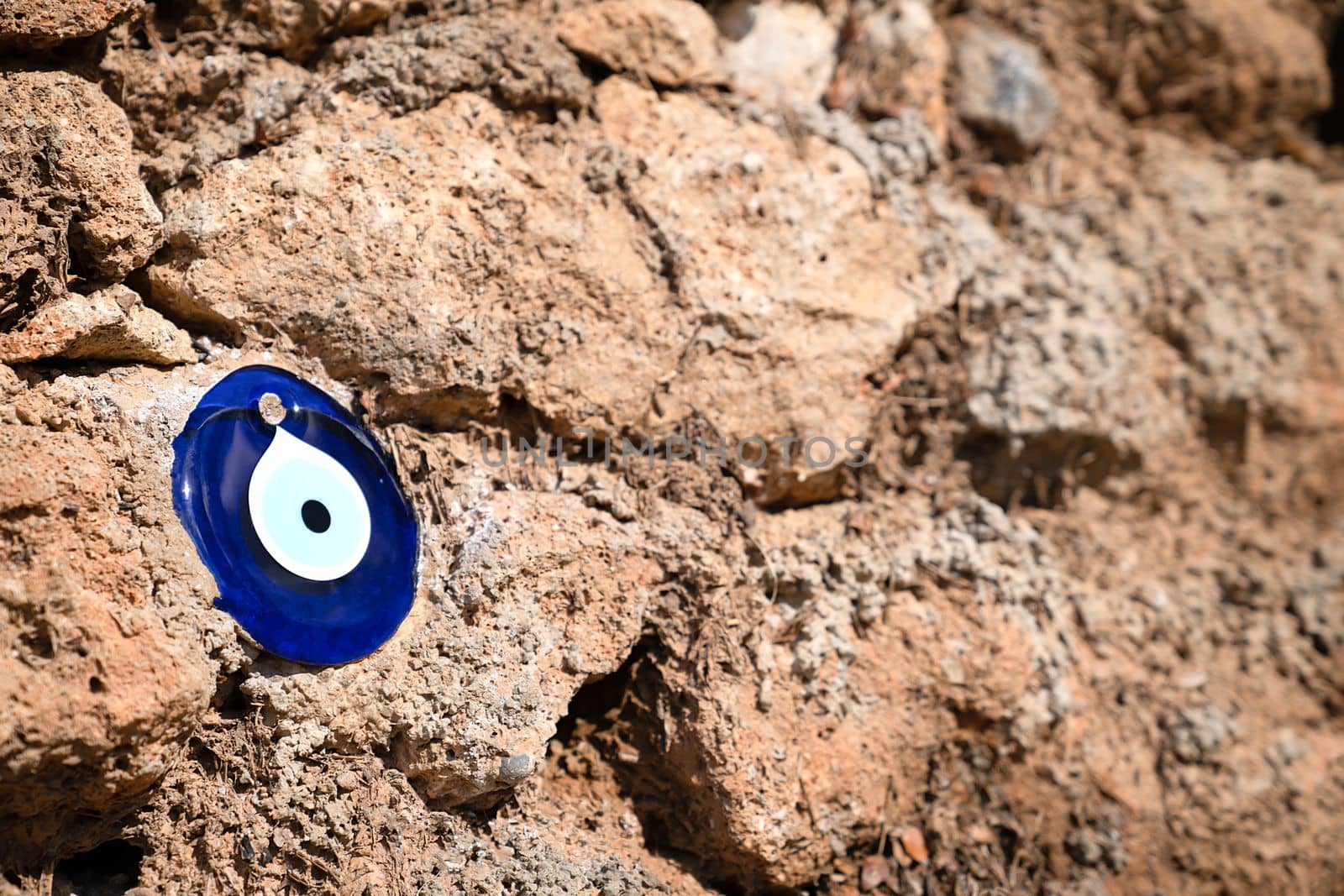 Blue glass eye of Fatima on brown stone background, a symbol of protection from evil eye, copy space