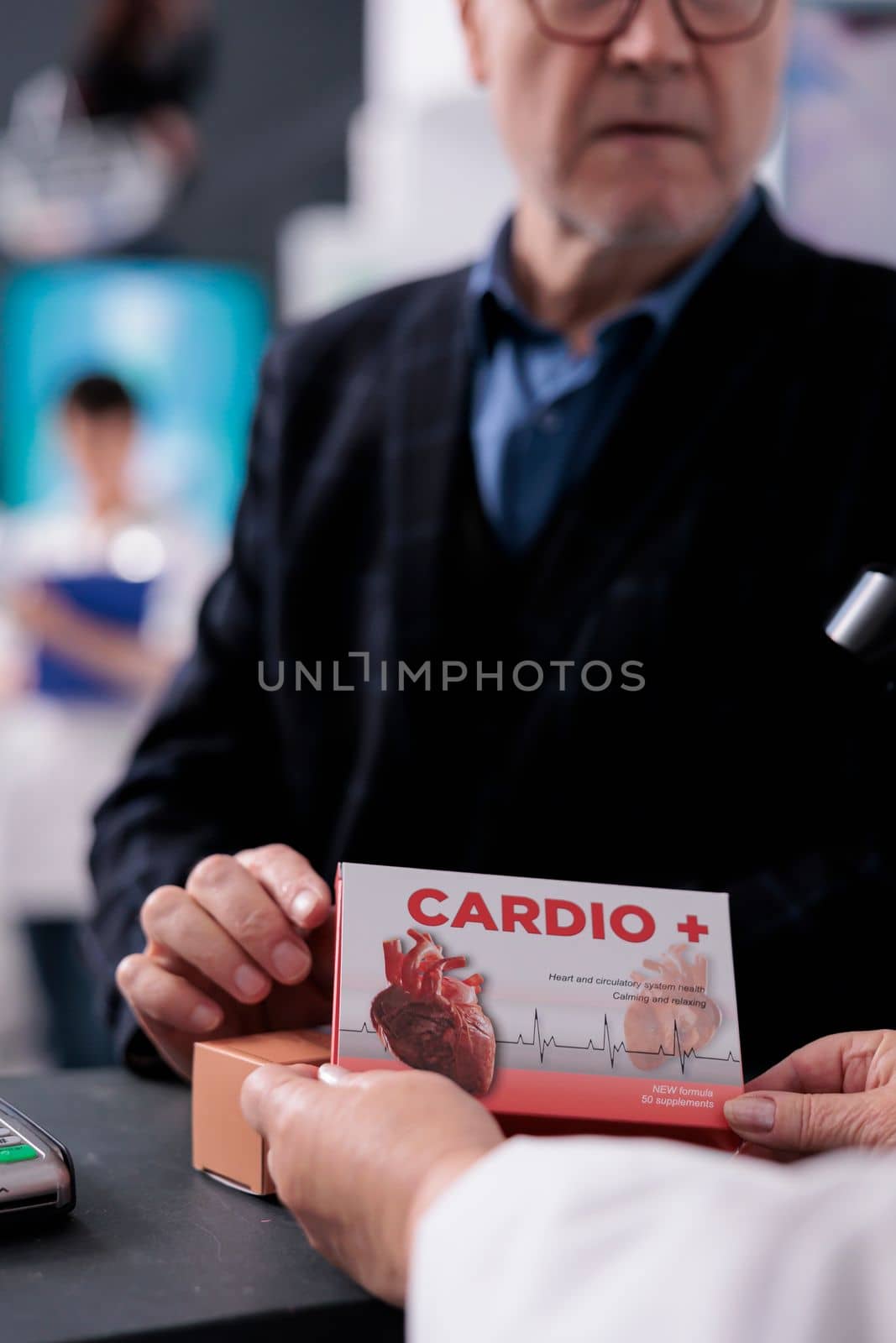 Old man consulting about heart medication at counter desk, asking drugstore cashier about supplements instruction explanation. Pharmaceutical assistant holding vitamin package at checkout close up