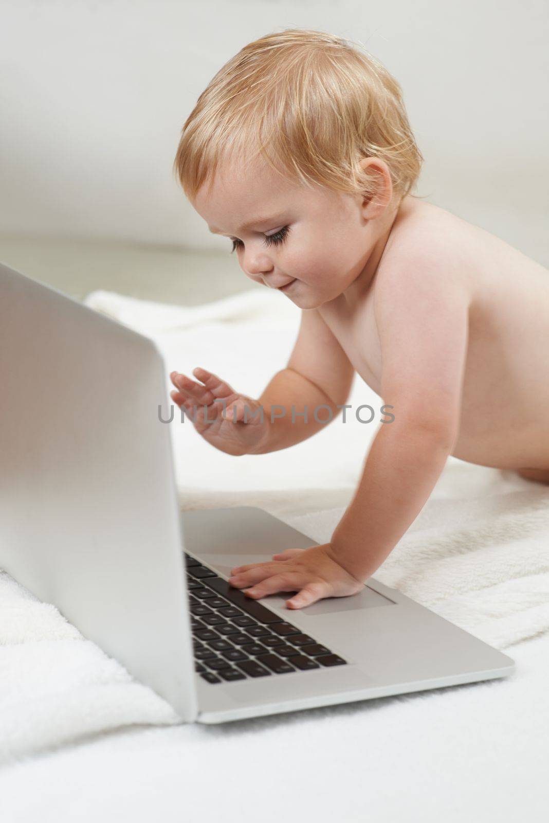 What does this button do...A baby taking interest in a laptop in front of him. by YuriArcurs