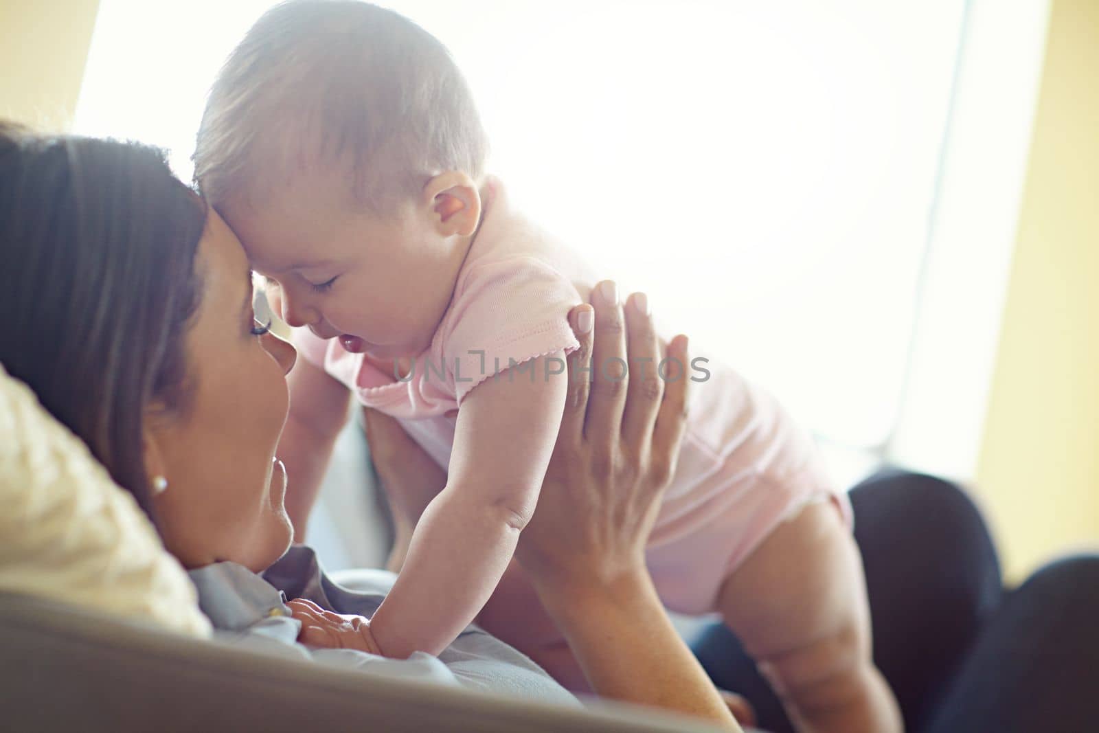 Mom, bonding or forehead touch with baby girl on house living room, relax nursery or family home sofa in trust or love. Smile, happy or infant child playing mother in support, security or relax game.