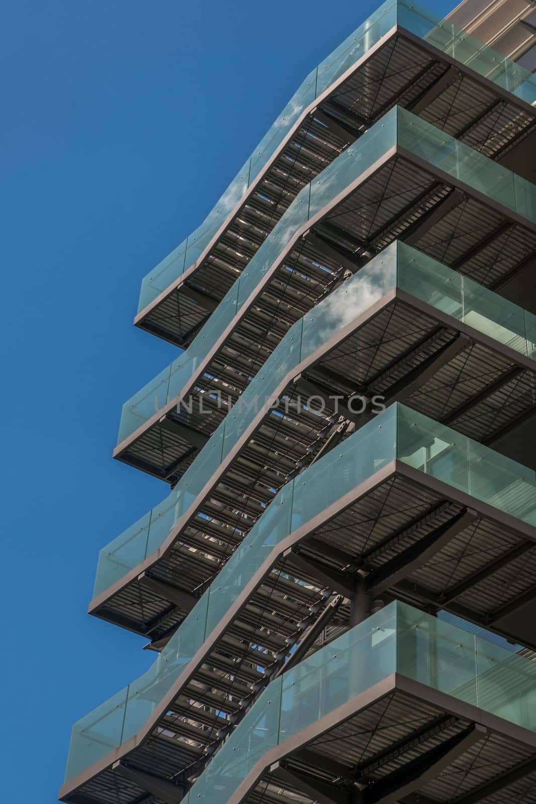 London 6 Jun 62 - Business building with metal emergency ladder / fire escape in modern office buildings with repeating structure and reflected sky and clouds.
