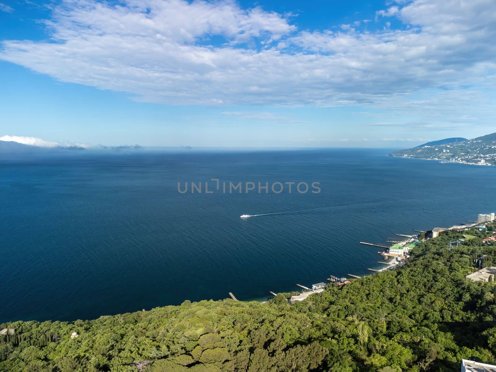 Sea landscape with rocky coastline on sunset time with cloudy sky. Yachts in the Sea on a background of rocky shores. The concept of perfect place for summer travel and rest.