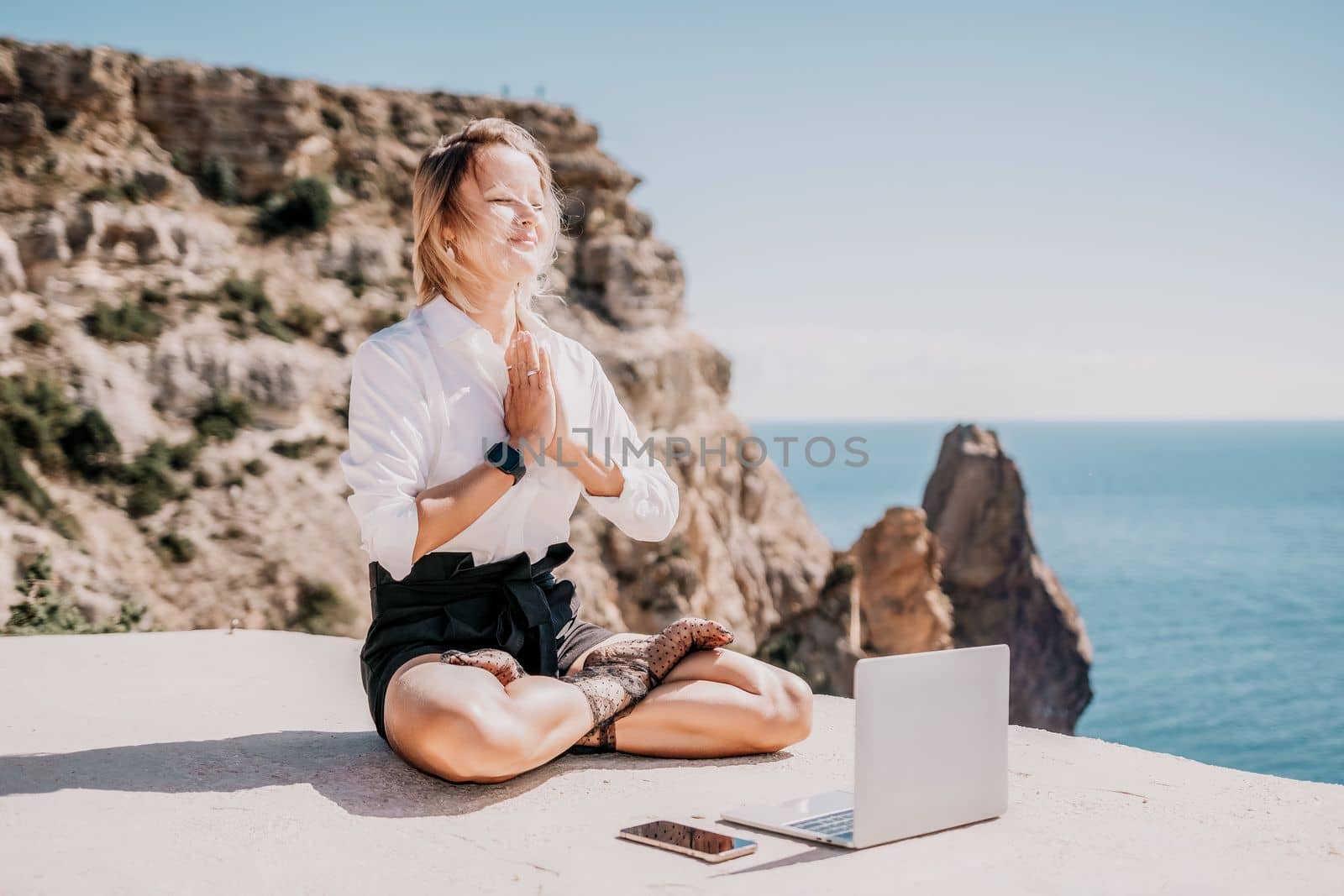 Woman sea laptop yoga. Business woman freelancer in yoga pose working over blue sea beach at laptop and meditates. Girl relieves stress from work. Freelance, digital nomad, travel and holidays concept by panophotograph