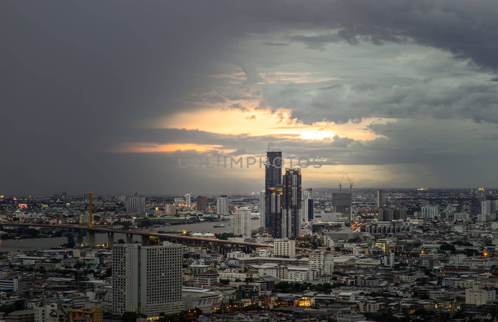 Bangkok, Thailand - 07 Jul 2021 : Aerial view of Beautiful sunset over large metropol city in Asia. There are prominent and isolated high-rise buildings along the Chao Phraya River. Selective focus.